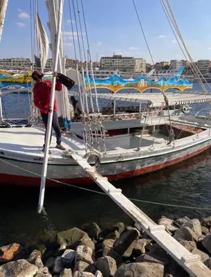 a person standing on a sail boat in the water at Rozan Guest house Aswan in Jazīrat Aswān