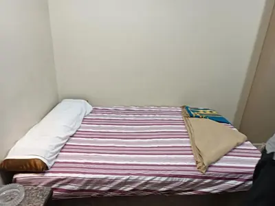 a bed with a striped blanket and pillows on it at فندق الإيمان El Eman Hotel in Maḩaţţat Idfū