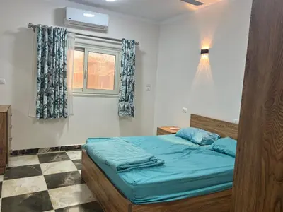 a bedroom with a bed with blue sheets and a window at Dream apartment2 in Hurghada
