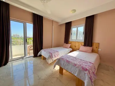 two beds in a room with a large window at Sylvie guest house in Luxor