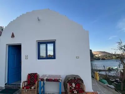 a white house with a blue door and chairs at Hannag Island Guest house in Aswan