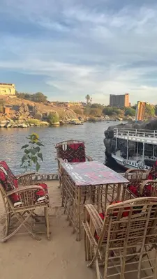 a group of tables and chairs next to a body of water at Hannag Island Guest house in Aswan