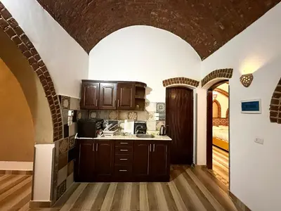 a kitchen with wooden cabinets and a brick wall at Sheherazade Hotel Nile Villa in Luxor