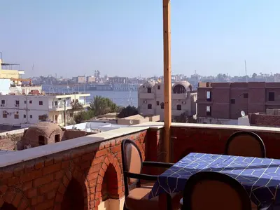 a table and chairs on a balcony with a view of the city at Sheherazade Hotel Nile Villa in Luxor