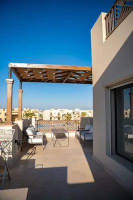 a balcony with chairs and tables on a building at 4 Bedrooms, Luxury Villa Makadi Heights in Hurghada