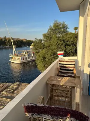a balcony with chairs and a boat on the water at Nile Bride in Aswan