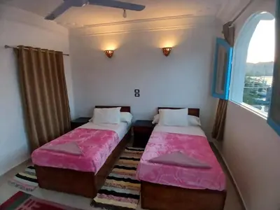 two beds in a small room with a window at Nile Bride in Aswan