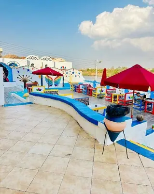 a pool with a water park with tables and umbrellas at Kulaih nubian guest house in Aswan