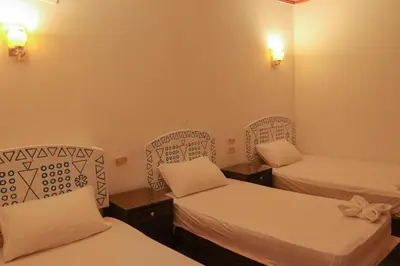 a room with two beds and two lights on the wall at Kulaih nubian guest house in Aswan