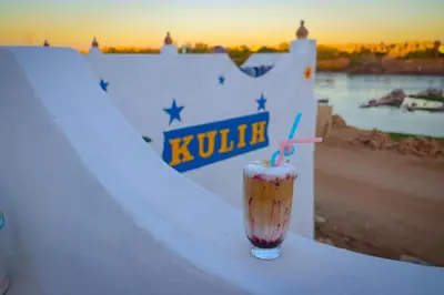 a drink sitting on a ledge with the sunset in the background at Kulaih nubian guest house in Aswan