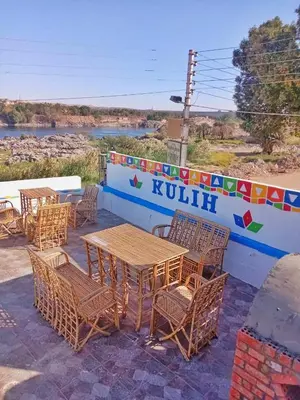 a group of tables and chairs next to a wall at Kulaih nubian guest house in Aswan