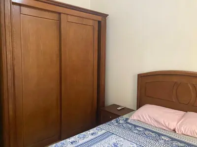a bedroom with a bed and a wooden cabinet at M-2bedroom flat with garden in Hurghada
