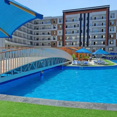 a bridge over a swimming pool in front of a building at Tiba Golden Resort one bedroom in Hurghada