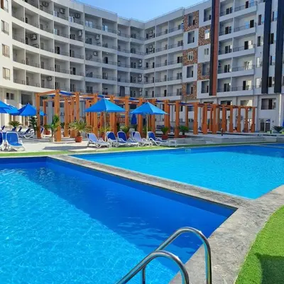 a large swimming pool in front of a large building at Tiba Golden Resort one bedroom in Hurghada