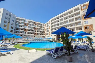 a swimming pool with chairs and blue umbrellas at Tiba Golden Resort one bedroom in Hurghada