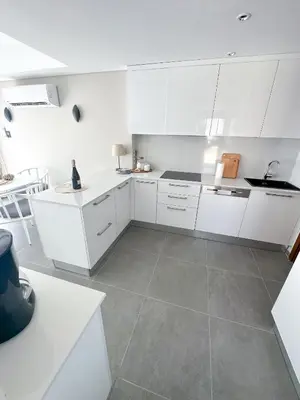 a kitchen with white cabinets and a tile floor at Supreme Beachfront 3BR Villa Soma bay with Garden in Hurghada
