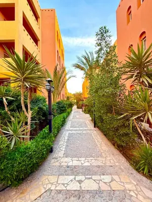 a stone path between two buildings with palm trees at Spacious 3BR Apartment - Al Dora Resort, Hurghada in Hurghada