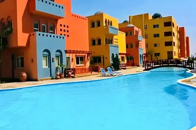 a swimming pool in a resort with colorful buildings at Spacious 3BR Apartment - Al Dora Resort, Hurghada in Hurghada