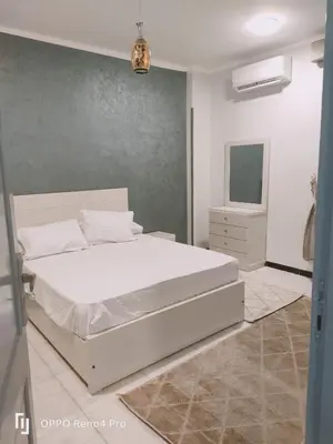 a bedroom with a white bed and a television at Lutos Flower Apartment in Luxor