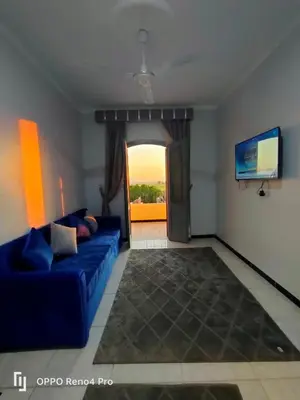 a living room with a blue couch and a window at Lutos Flower Apartment in Luxor