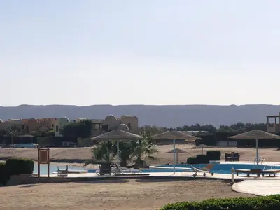 a swimming pool with umbrellas and chairs and tables at one bedroom ground floor sabina elgouna in Hurghada