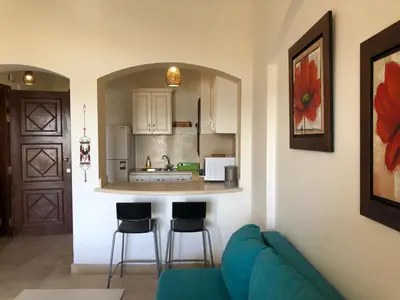 a living room with a blue couch and a kitchen at one bedroom ground floor sabina elgouna in Hurghada