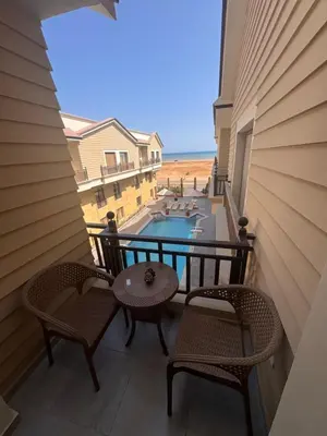 a balcony with two chairs and a table and a pool at Aqua blue bay in Hurghada