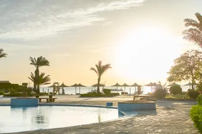 a pool at a resort with palm trees and umbrellas at Hurghada Khaligeya village in Hurghada