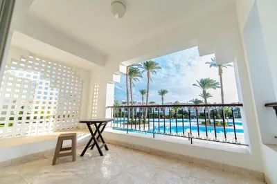 a room with a balcony with a view of the pool at Hurghada Khaligeya village in Hurghada