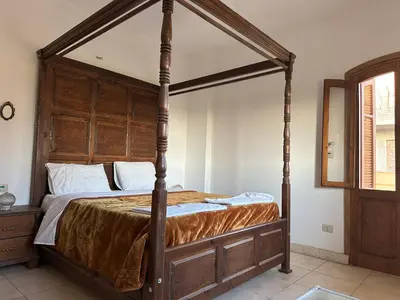a canopy bed with a wooden frame in a bedroom at Sunset Haven in Luxor