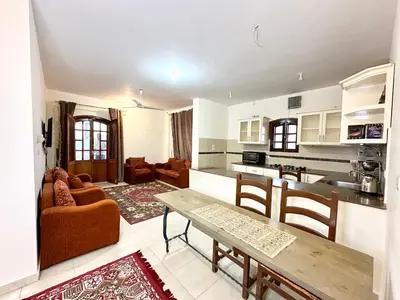 a living room with a table and a kitchen at Sunset Haven in Luxor