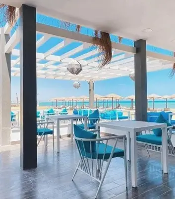 a dining room with blue chairs and tables and the ocean at Fanadir bay compound in Hurghada