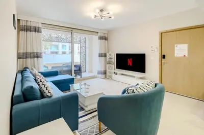 a living room with two blue chairs and a tv at Homestyle & Summery 1BDR Mangroovy Free Beach Pool in Hurghada