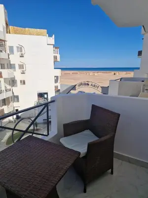 a chair and a table on a balcony with the beach at Tiba View in Hurghada