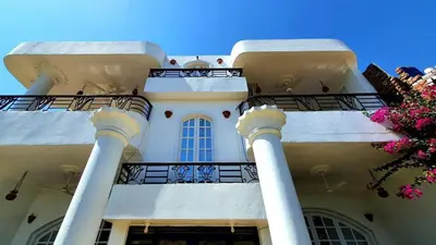 a white building with two columns and a balcony at Blue Lotus House in Luxor
