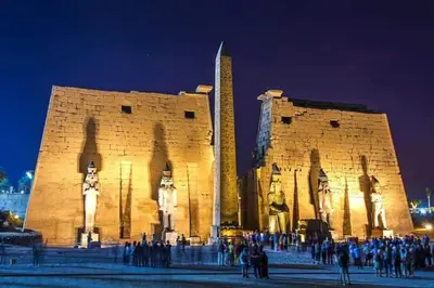 a group of people standing outside a building at night at البعيرات in Al Karnak