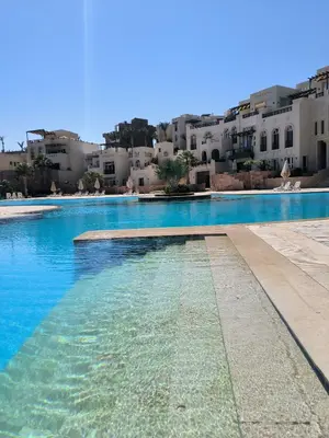 a swimming pool with blue water in front of buildings at Elite 3bdr apartment with garden beside corral reef in Hurghada
