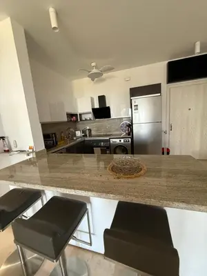 a kitchen with a granite counter top and black stools at Elite 3bdr apartment with garden beside corral reef in Hurghada