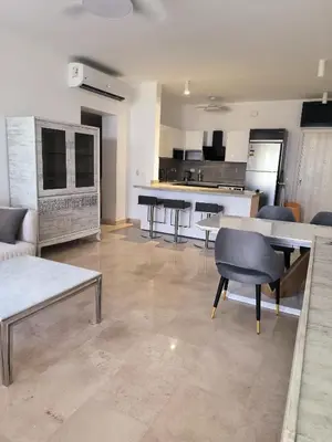a living room with a table and chairs and a kitchen at Elite 3bdr apartment with garden beside corral reef in Hurghada