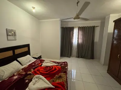 a bedroom with a bed with red blankets on it at The Highlander in Al Karnak