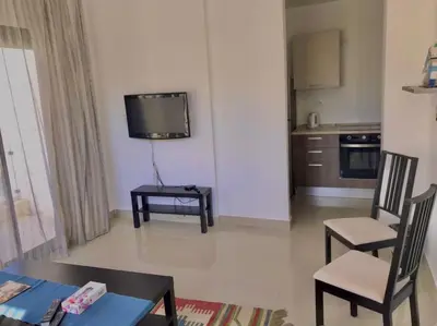 a living room with a tv and a table and chairs at Stunning 1-Bedroom in G Cribs in Hurghada