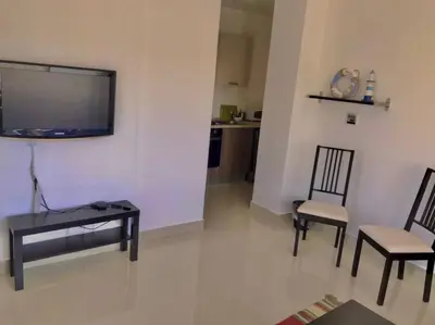 a living room with two chairs and a flat screen tv at Stunning 1-Bedroom in G Cribs in Hurghada