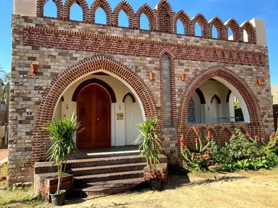 a brick building with a brown door and some plants at ELamir house in Al Aqālitah