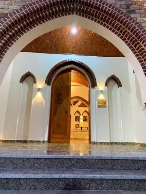 an archway leading into a building with a wooden door at ELamir house in Al Aqālitah