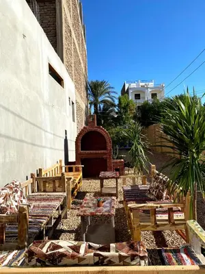 a courtyard with wooden tables and benches next to a building at ELamir house in Al Aqālitah