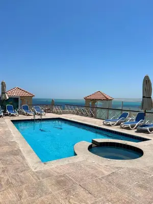 a swimming pool with chairs and the ocean in the background at Luxurious One Bedroom Apartment in Hurghada