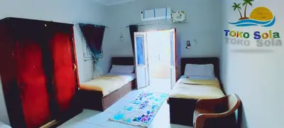 a room with two beds and a chair in it at Toko Sola in Jazīrat Suhayl