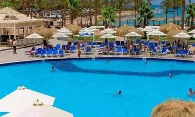 a large swimming pool with blue chairs and umbrellas at Mirage Bay Resort & Aqua Park in Hurghada