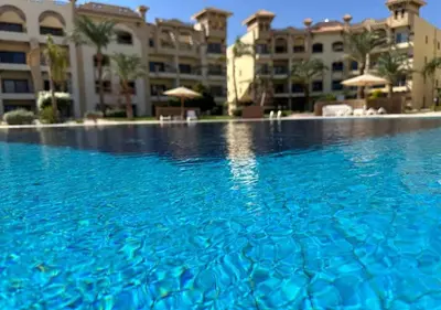 a swimming pool with blue water in front of a building at Resort-Style Luxury Chalet with Pool and Sea View in Sahl Hasheesh in Hurghada