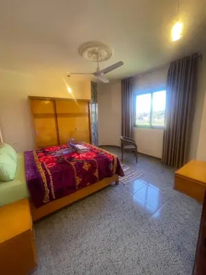 a bedroom with a bed and a chair and a window at Flat in Kom in Luxor